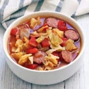 Cabbage soup is served in a white soup bowl.