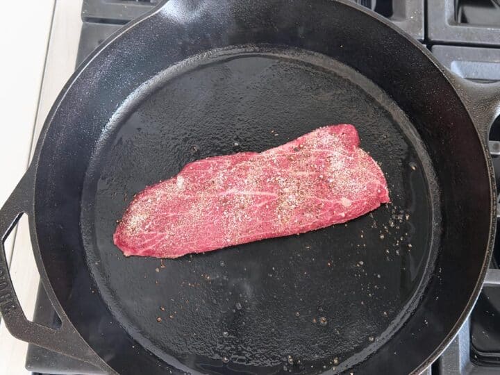 Flat iron steak in a cast-iron skillet.