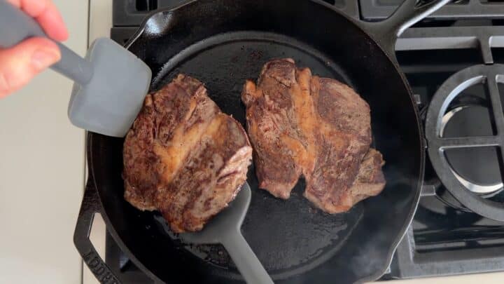 Flipping the steaks to finish cooking.