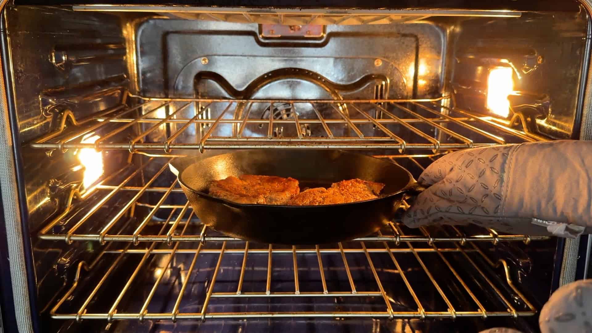 Placing the steaks in the oven to finish cooking.