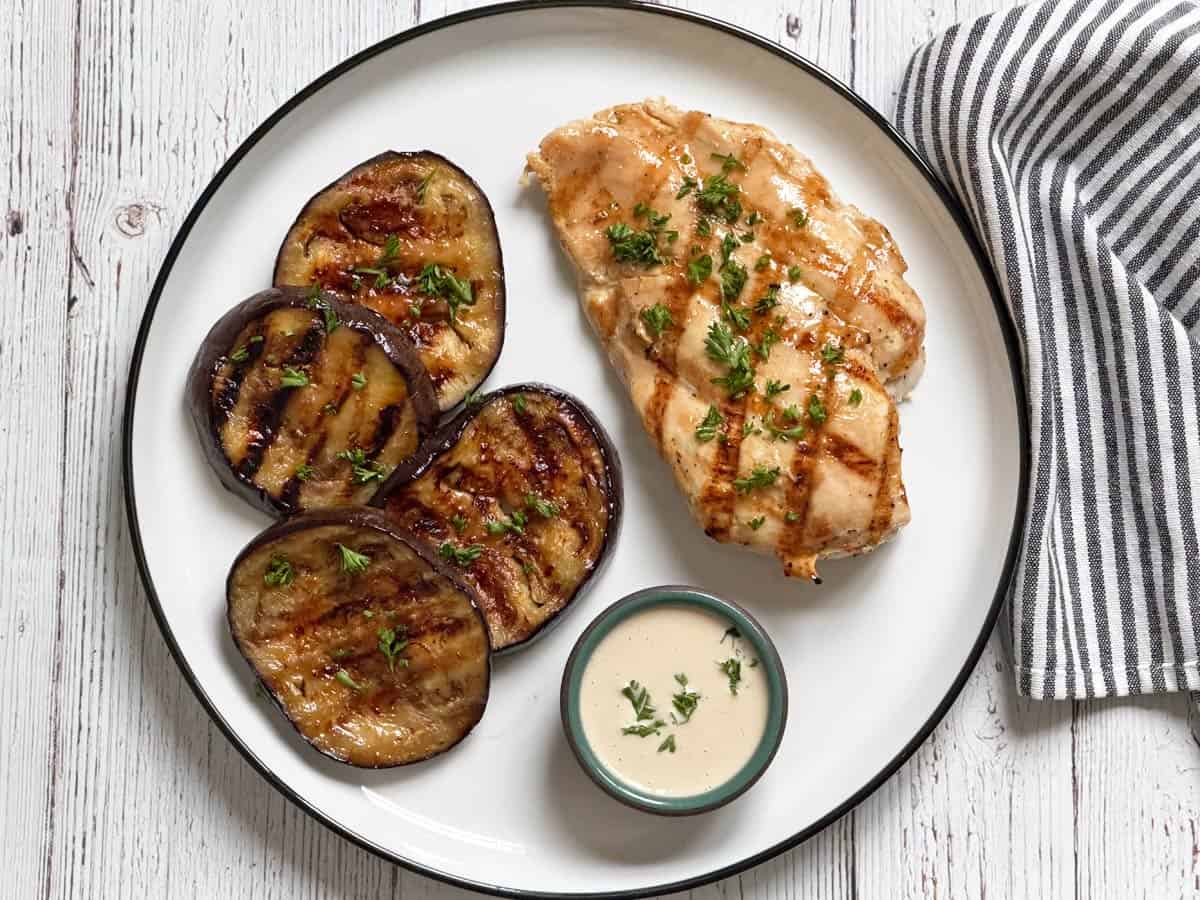 Grilled eggplant is served with grilled chicken and tahini sauce.