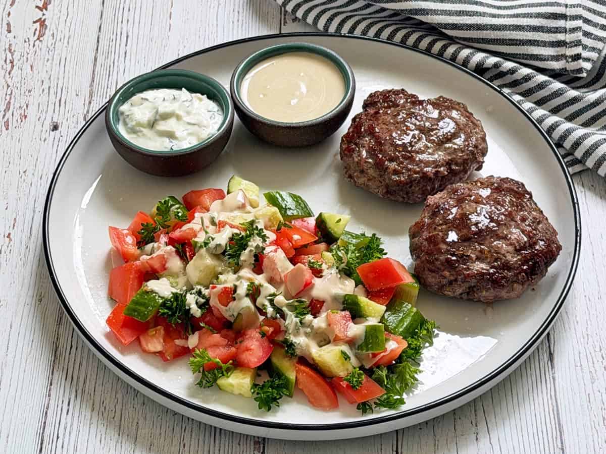 Lamb burgers are served with Israeli salad.