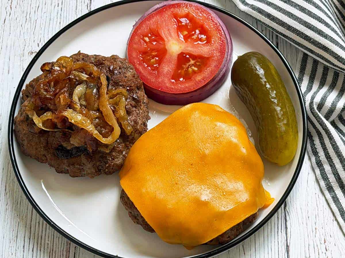 Grilled burgers are topped with melted cheese and caramelized onions.